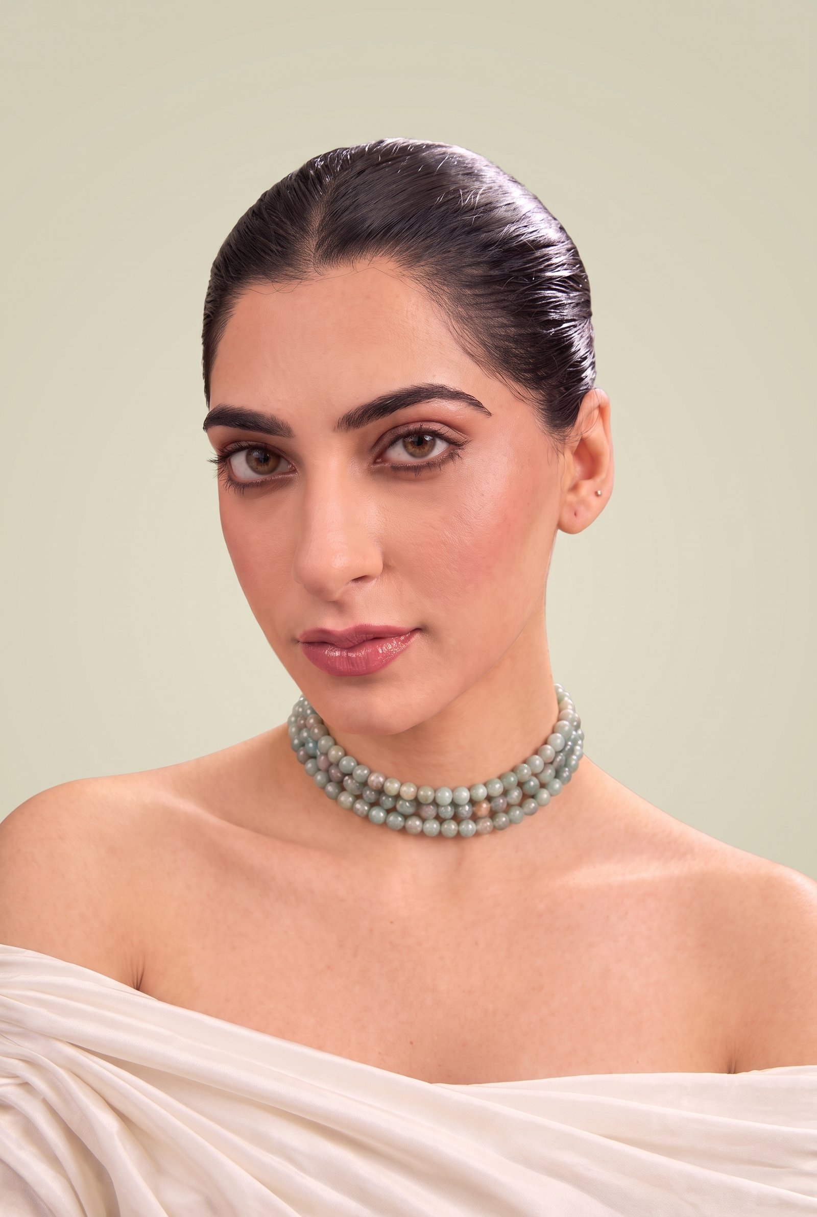 A woman in a white off-shoulder drape wearing the Dusk Pearl Trio sage bead choker