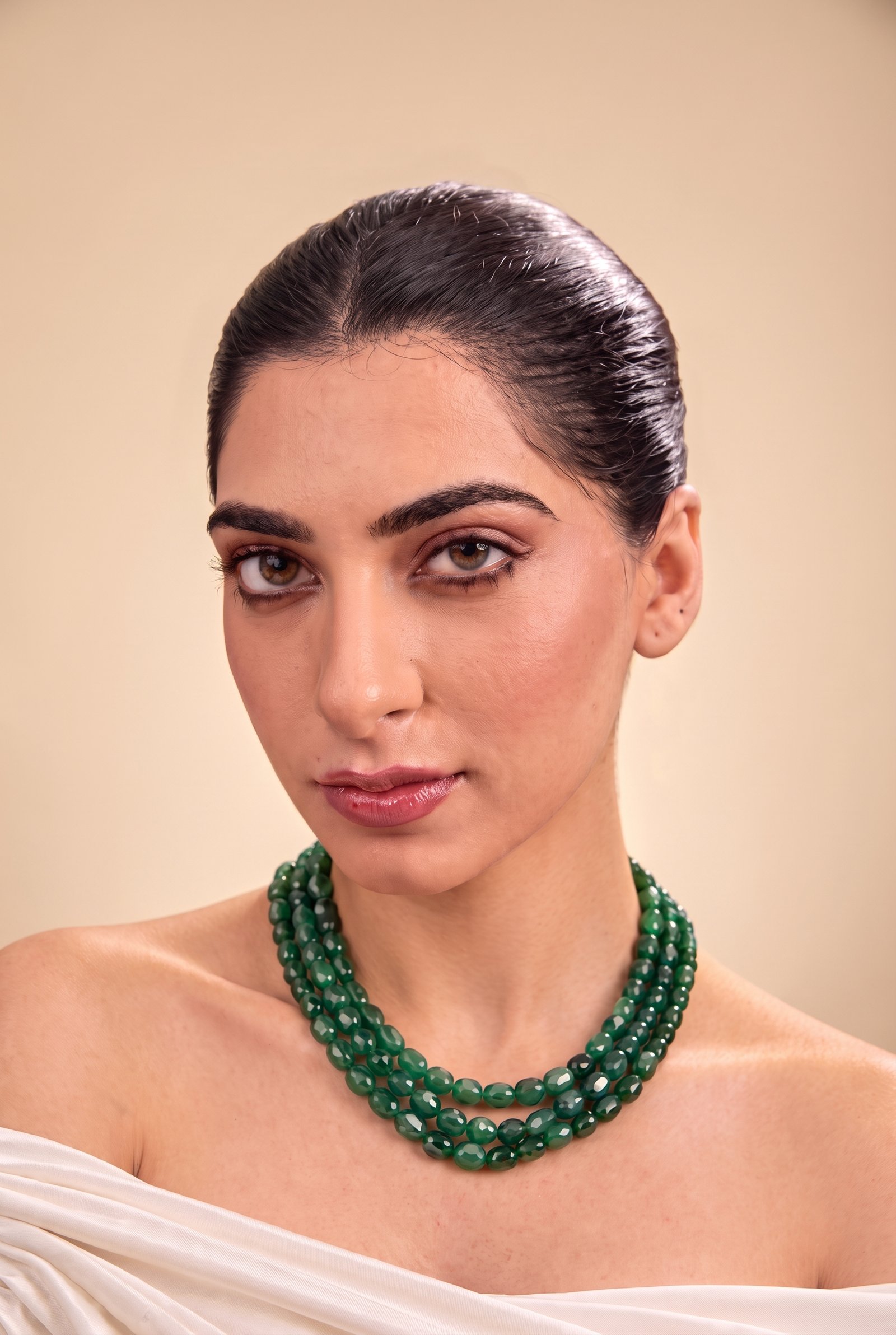A woman in a white off-shoulder drape wearing the Deep Emerald Trio green bead choker