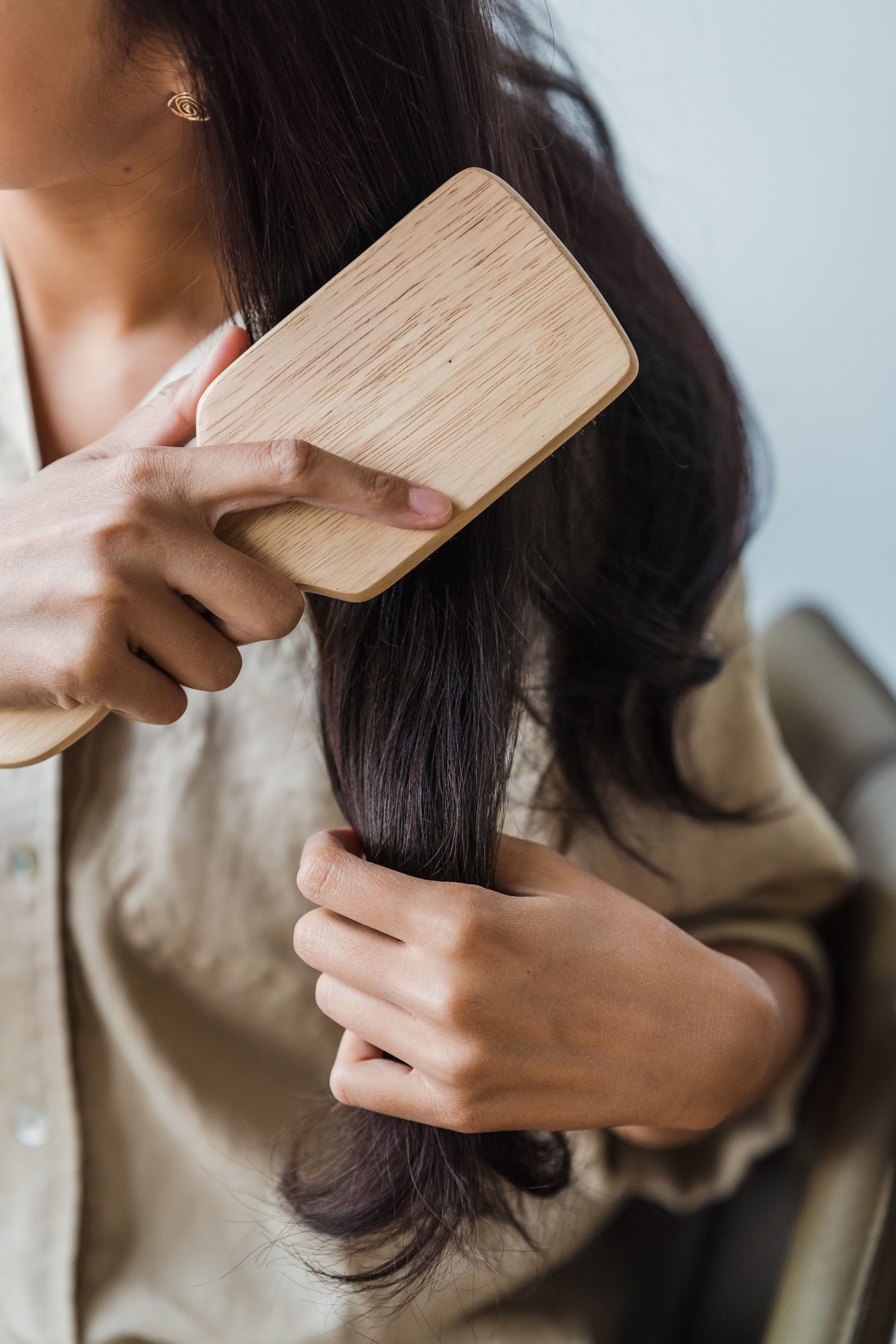 Close-up of a woman brushing long dark hair in warm light
