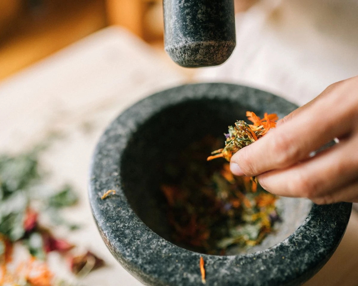 Hands preparing dried herbs in a stone mortar