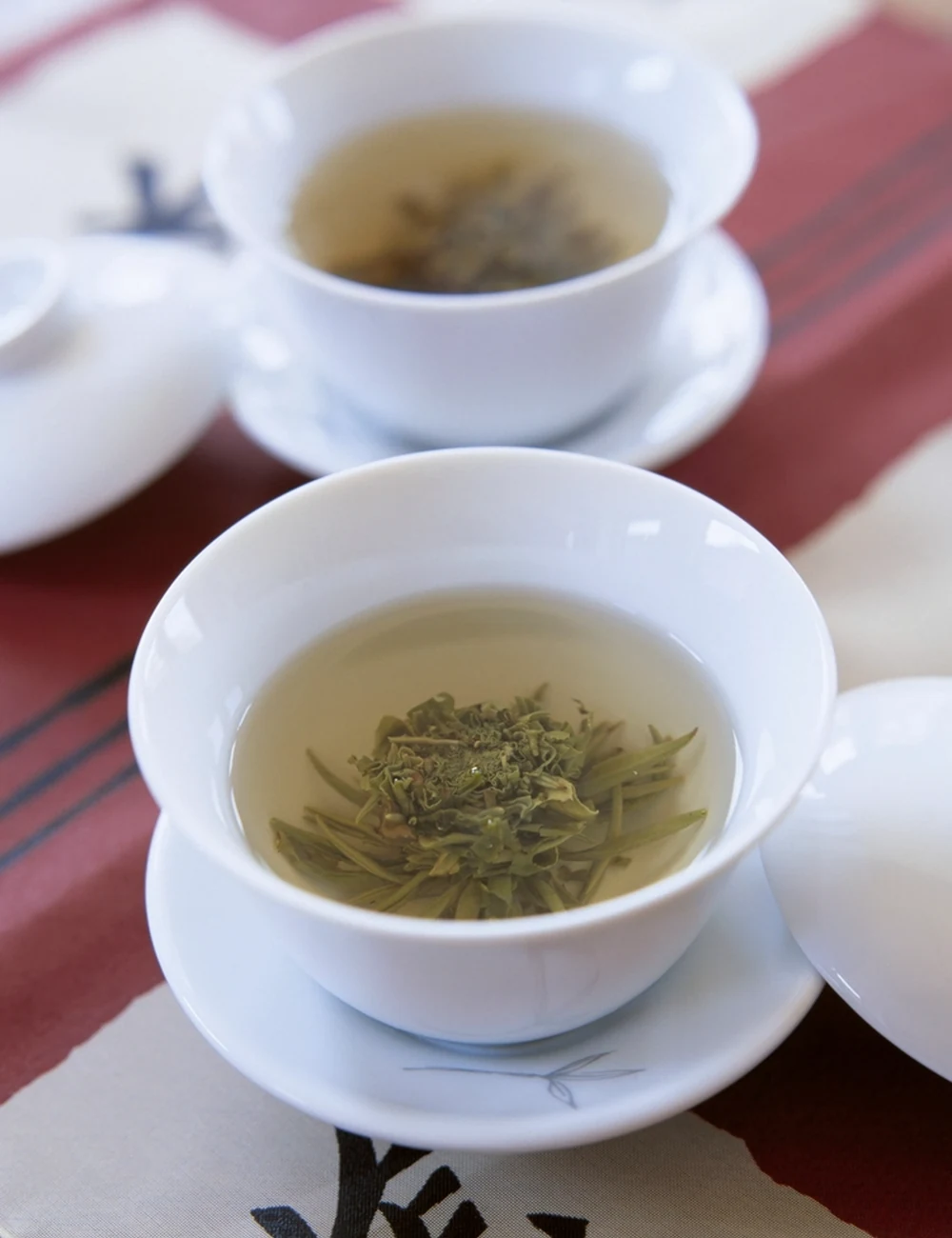 Loose green tea steeping in white ceramic cups