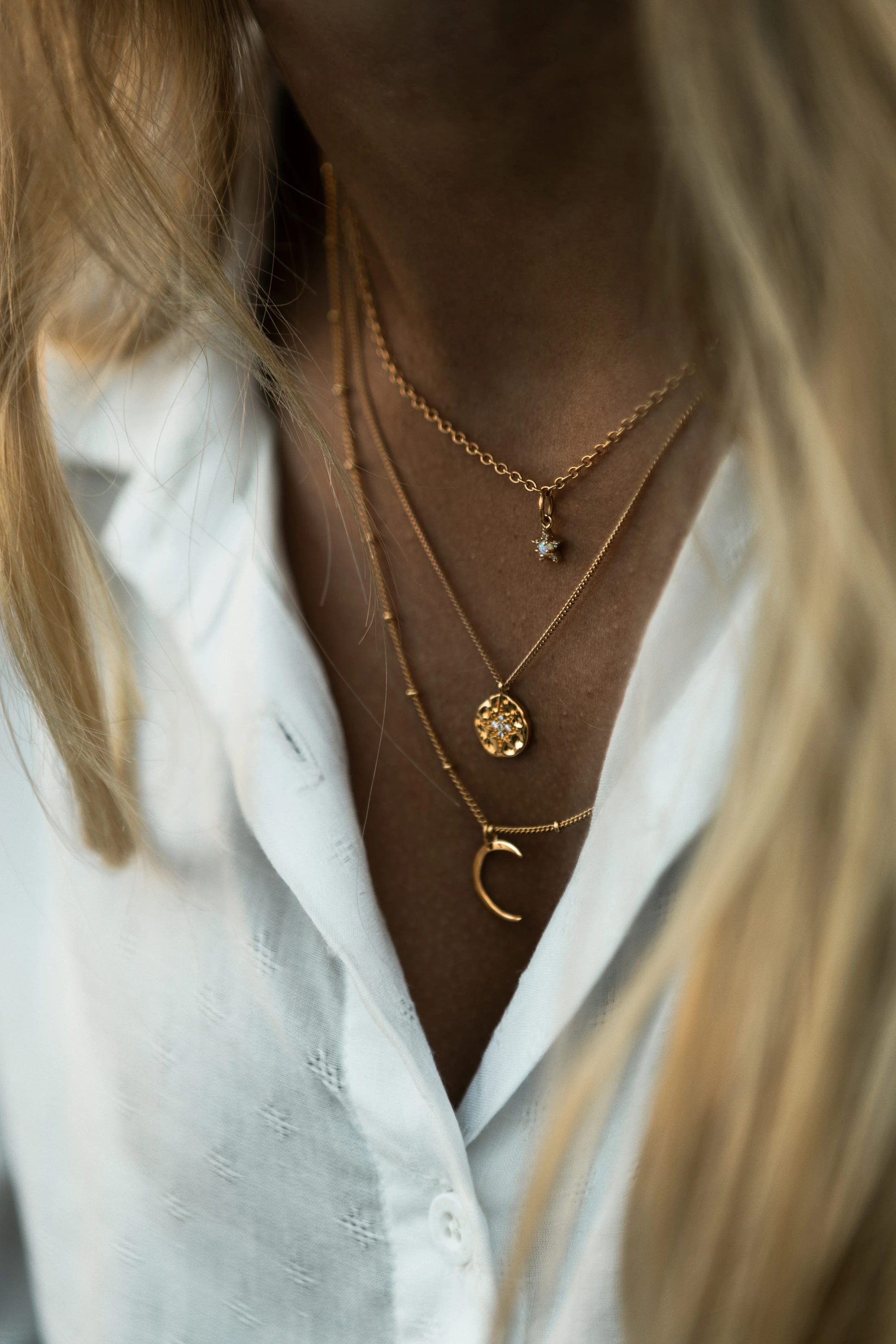 Layered gold necklaces worn with a white shirt